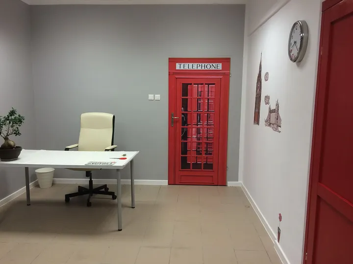 Sala z biurkiem, fotelem i dekoracją czerwonej brytyjskiej budki telefonicznej na ścianie