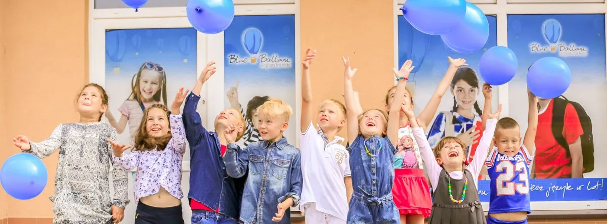 Dzieci z niebieskimi balonami przed szkołą Blue Balloon w Słupsku
